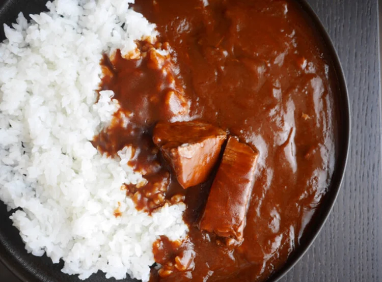 White rice beside dark curry sauce with visible chunks