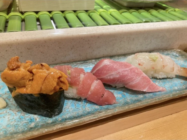 Sea urchin gunkan, tuna nigiri, and white fish nigiri on a blue plate